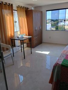 a room with a table and a bed and a window at Regina in Cabo Frio