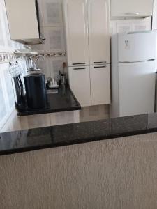 a kitchen with white cabinets and a white refrigerator at Regina in Cabo Frio +2 photos