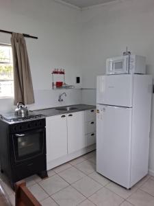 eine Küche mit weißen Geräten und einem schwarzen Herd und Kühlschrank in der Unterkunft Casita de Campo - Chacra Lavanda in Salto + 18 Fotos