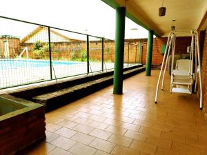 a porch with a swing and a tennis court at Posada Familiar ELDORADO in Eldorado