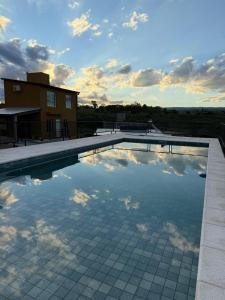 a swimming pool with a reflection of clouds in the water at Cabañas La Caprichosa in Villa Santa Cruz del Lago