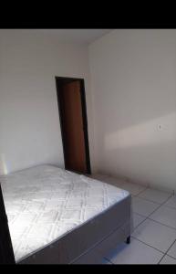 a white bed in a white room with a door at Casa indisponíve in Maracaju