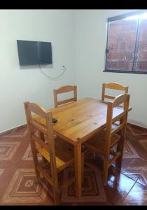a wooden table with two chairs and a television on a wall at Casa indisponíve in Maracaju