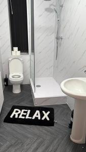 a bathroom with a shower toilet and a sign that says relax at Check Inn 247 in Bradford