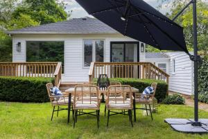 een tafel met stoelen en een parasol voor een huis bij New Modern Home in Old Town in Niagara on the Lake