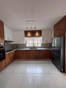 a kitchen with wooden cabinets and a black refrigerator at Residencia Flores in Hermosillo