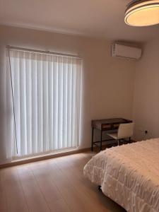 a bedroom with a bed and a desk and a large window at Residencia Flores in Hermosillo