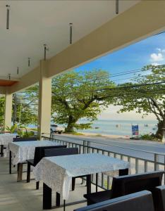 een terras met tafels en uitzicht op het strand bij Mukrada House Boutique Hometel Krabi in Klong Muang Beach