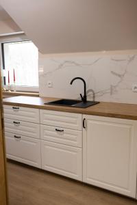 a kitchen with white cabinets and a sink and a window at Apartamenty obok Suntago Park of Poland parking gratis in Wręcza