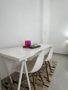 a white table with two chairs and a plate with wine glasses at Suite 1 com Ar-Condicionado, TV, Wi-Fi e Geladeira in Jundiaí