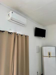 a room with a refrigerator and a television on the wall at Suite 1 com Ar-Condicionado, TV, Wi-Fi e Geladeira in Jundiaí