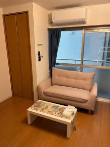 a living room with a couch and a coffee table at 202basichostel in Osaka