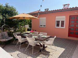 a patio with a table and chairs and an umbrella at Quinta das Rosas - Beach 500m away in Figueira da Foz