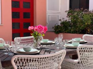 a wooden table with white chairs and pink flowers at Quinta das Rosas - Beach 500m away in Figueira da Foz