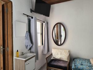 een badkamer met een wastafel, een spiegel en een stoel bij SuÍte 4 Completa com Wi-Fi e Netflix in Jundiaí