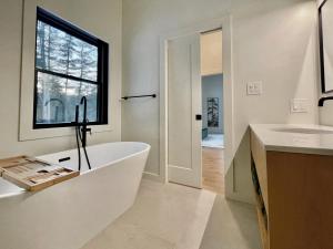 un bagno con vasca, lavandino e finestra di White Pine Chalet a Yulan Altre 37 foto