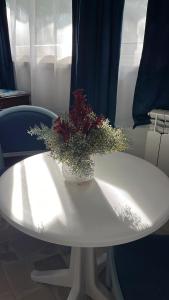 un tavolo bianco con un vaso di fiori sopra di B&B Villa Mediterranea with parking space a Trani
