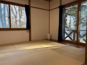 an empty room with a window and a rug at Pebble Mountain Cabin in Shinano