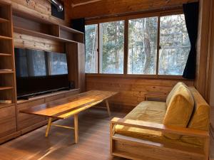 a room with a table and a tv in a cabin at Pebble Mountain Cabin in Shinano