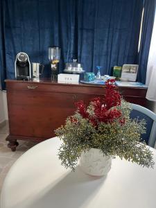 un tavolo bianco con un vaso con fiori rossi di B&B Villa Mediterranea with parking space a Trani