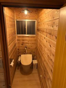 a bathroom with a toilet in a wooden wall at Pebble Mountain Cabin in Shinano +38 photos