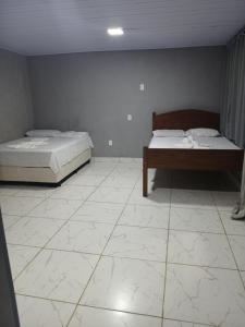 1 Schlafzimmer mit 2 Betten und Fliesenboden in der Unterkunft Kitnet na mata atlantica in Ubatuba + 2 Fotos