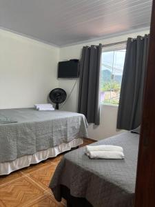 a bedroom with two twin beds and a window at Pousada Sol e Mar Dias Cezar in Paraty