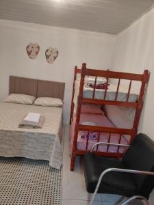 a small room with a bunk bed and a chair at Pousada do Coqueiro in São Gabriel