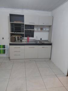 a kitchen with white cabinets and a black counter top at Pousada do Coqueiro in São Gabriel