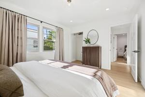 a white bedroom with a large bed and a mirror at Casa Yano by The Beach in Santa Barbara