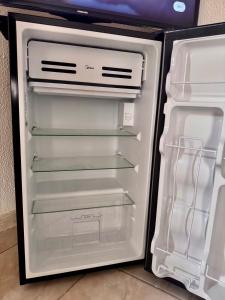 een lege koelkast met de deur open in een keuken bij Suíte 2 Completa - Wi-Fi e Netflix in Jundiaí