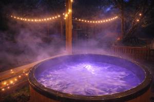a jacuzzi tub in a yard with lights at Osada Brzeziny - 25 minut od Warszawy - sauna, balia z jacuzzi, basen, altana, grill, ogród, ognisko in Brzeziny