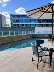 een tafel en stoelen met een parasol naast een zwembad bij Cupe Living - VSH in Porto De Galinhas