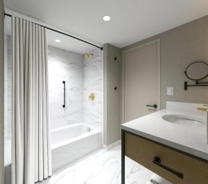 a white bathroom with a tub and a sink at Hotel Kelowna & Conference Centre in Kelowna