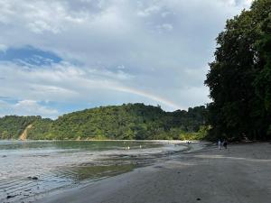 a rainbow over a beach with people walking on the sand at Hospedaje el Argentico in Tapantí