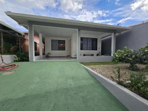 a white house with a green driveway at Casa Burbujas in Puerto Jiménez