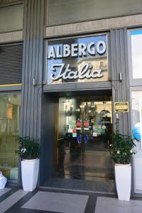 an entrance to an albergo hilton with two potted plants in front at Hotel Italia City Center in Mantova