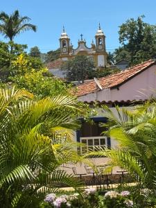 a building with a clock tower and palm trees at Pousada Arco íris na Serra in Tiradentes