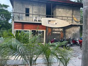 een gebouw met een balkon met daarvoor geparkeerde motorfietsen bij Phayam Hostel in Ko Phayam
