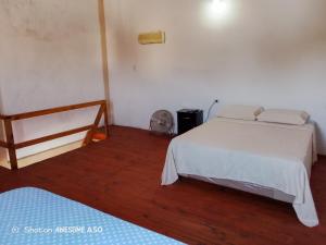 a bedroom with a white bed and a wooden floor at Complejo la Raquel in Goya
