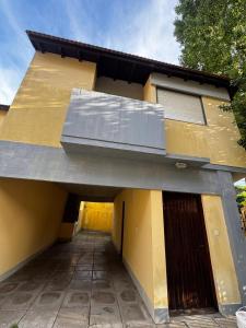 une maison jaune avec un toit et un garage dans l'établissement Duplex amplio y tranquilo 3habs 2baños, à San Bernardo