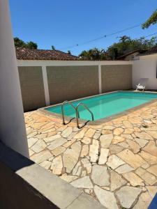 a swimming pool with a stone walkway around it at Pousada Arco íris na Serra in Tiradentes