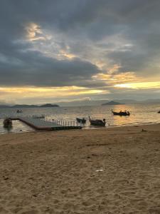 een strand met twee boten in het water bij Phayam Hostel in Ko Phayam