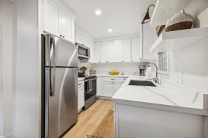 a kitchen with white cabinets and a stainless steel refrigerator at Casa Yano by The Beach in Santa Barbara