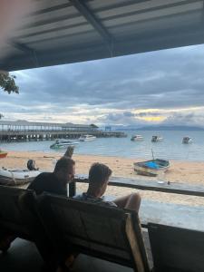 two men sitting on a bench near the beach at Phayamhostel in Ko Phayam
