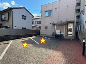 three stars in a parking lot in front of a building at 民泊 Ichinomiya K Room 2B in Ichinomiya