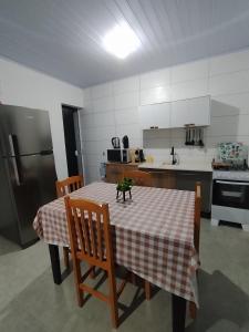 een keuken met een tafel, stoelen en een koelkast bij Casa temporada estrela do mar in Imbé