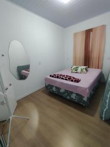 een slaapkamer met een bed en een spiegel aan de muur bij Casa temporada estrela do mar in Imbé