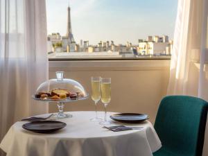 een tafel met twee glazen champagne en een bord eten bij Mercure Paris Montparnasse Pasteur in Parijs