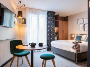een hotelkamer met een bed, een tafel en stoelen bij Mercure Paris Montparnasse Pasteur in Parijs